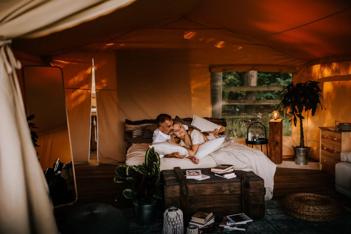Kobieta i mężczyzna leżą na łóżku w namiocie w Kimura Glamping Cicha 23 na sesji narzeczeńskiej